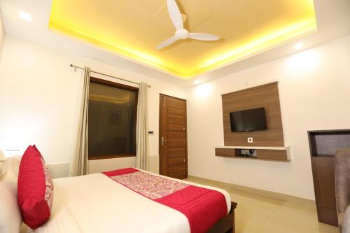a bedroom with a bed with a ceiling fan and a tv at Hotel Lavit Couple Friendly near Faridabad Metro station in Faridabad