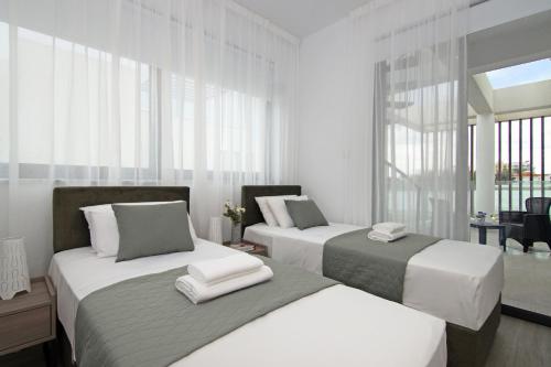 twee bedden in een kamer met wit en grijs bij Villa Queen Eleanor in Protaras