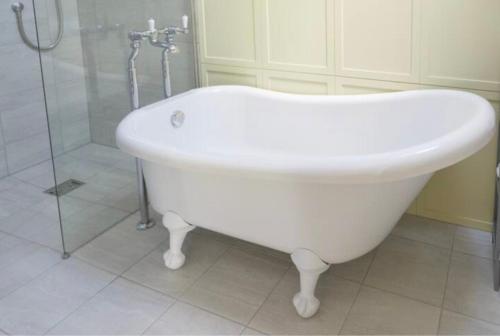 a white bath tub in a bathroom with a shower at The Silver Birch Cottage - Greentrees Estate in Haywards Heath