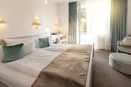 a bedroom with a large white bed and a chair at Hotel Traube Revital in Wurmlingen