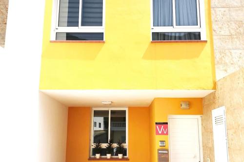 un bâtiment jaune avec deux fenêtres et des plantes en pot dans l'établissement MIRADOR DE MERESE, à Frontera