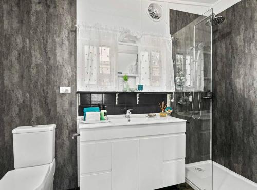 a bathroom with a white sink and a shower at Coastal Vibes - Walk to beach, Marina, Cafes and Pubs in Shellharbour