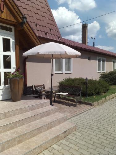 a patio with a table and an umbrella in front of a house at Kata Panzió in Oroszlány