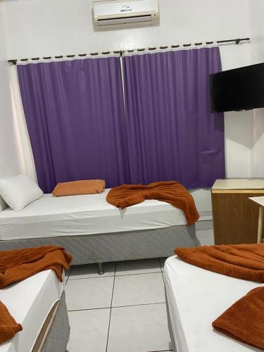 um quarto com 2 camas e uma cortina roxa em HOTEL REAL em Marechal Cândido Rondon
