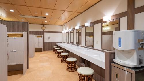 Cette grande chambre comprend une rangée de lavabos et de tabourets. dans l'établissement KAMENOI HOTEL Atami Annex, à Atami