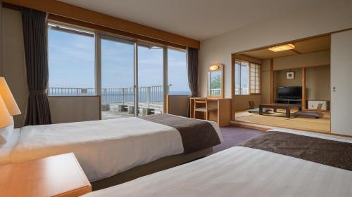 a hotel room with two beds and a balcony at KAMENOI HOTEL Atami Annex in Atami