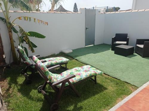 a patio with two chairs on the grass at Habitación privada con baño y jardín privado in Chiclana de la Frontera