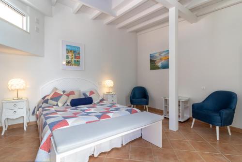 - une chambre blanche avec un lit et deux chaises bleues dans l'établissement Casa Monsoria, à Carvoeiro