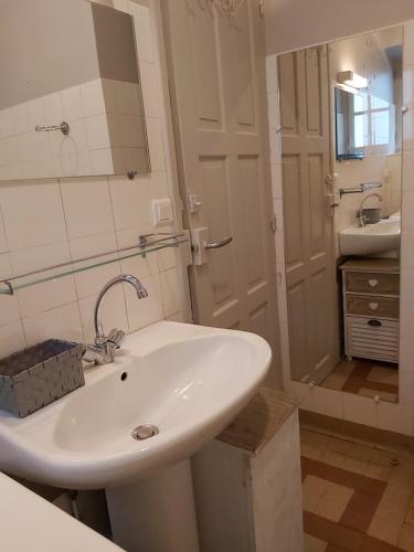 une salle de bain blanche avec un lavabo et un miroir dans l'établissement Le capucin, à Le Mont-Dore