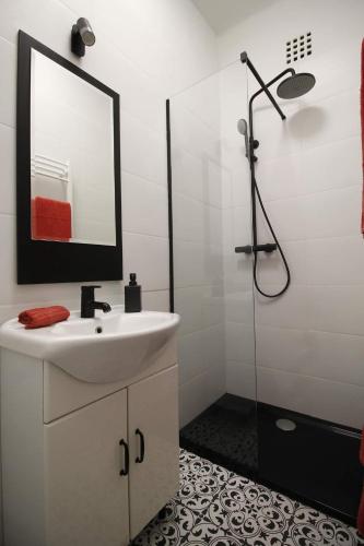 a bathroom with a sink and a shower with a mirror at Viktória stúdióapartman in Győr