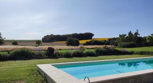 una piscina en un patio con un campo de flores en L`Atelier en Saint-Martial-Viveyrol