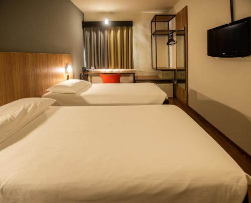 a hotel room with two beds and a flat screen tv at ibis Betim in Betim