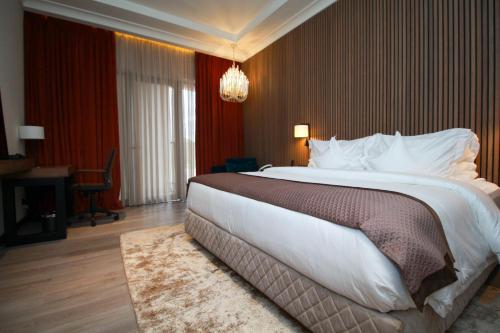 ein großes Bett in einem Hotelzimmer mit einem Kronleuchter in der Unterkunft D'avenue Boutique Hotel Accra in Accra
