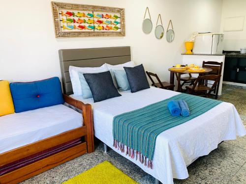 a bedroom with two beds and a table with a kitchen at Flat vista incrível in Arraial do Cabo