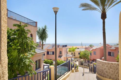 a view of a street with buildings and a palm tree at Free Airport Shuttle and Parking in San Bartolomé de Tirajana
