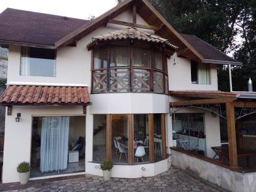 une maison avec des fenêtres en verre et un toit dans l'établissement Casa de fino acabamento e conforto em Monte verde, à Monte Verde