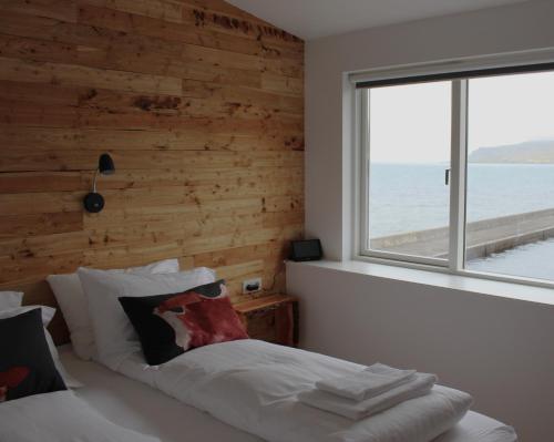 1 dormitorio con pared de madera y 1 cama con ventana en Blabjorg Resort en Borgarfjordur Eystri