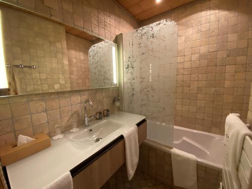 a bathroom with a tub and a sink and a mirror at Hôtel Macchi Restaurant & Spa in Châtel