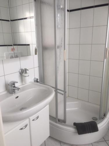 La salle de bains blanche est pourvue d'une douche et d'un lavabo. dans l'établissement Ferienwohnung Bruni I, à Oldenbourg