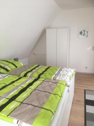 - une chambre dotée d'un lit avec des draps verts et gris dans l'établissement Ferienwohnung Bruni I, à Oldenbourg
