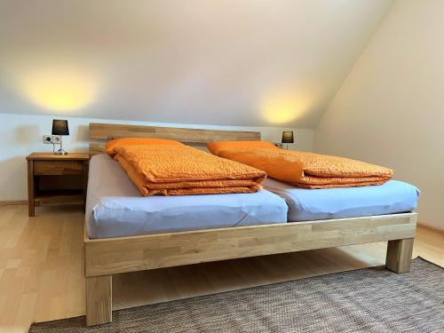 a bedroom with a bed with orange pillows on it at Ferienwohnung Kinzigblick - Balkon - Für Kinder - mit Bettwäsche & Handtücher in Schenkenzell