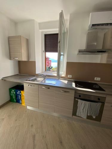 a kitchen with a sink and a stove and a window at Around Lago Maggiore apartments in Reno Di Leggiuno