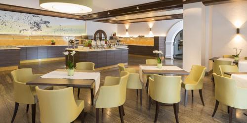 a restaurant with tables and chairs and a counter at Hotel Akazienhaus in Herzogenaurach
