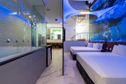 a hotel room with two beds and a bathtub at Drops Motel Manaus in Manaus