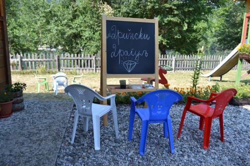 four colorful chairs sitting in front of a chalkboard at Drinski dragulj in Višegrad