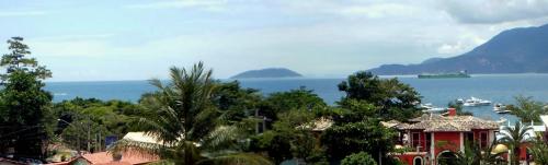 a view of the ocean and a house with trees at Pousada Mareilha in Ilhabela