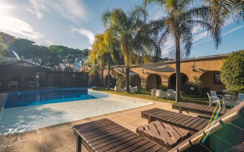 a swimming pool with two wooden benches and palm trees at Hacienda Don Justo Hotel Boutique Spa in Colón