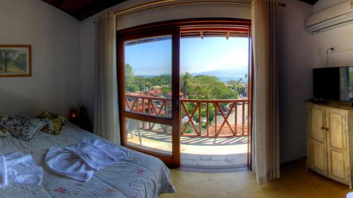 a bedroom with a bed and a large window with a balcony at Pousada Mareilha in Ilhabela