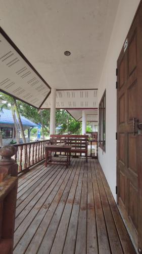 un porche vacío con bancos y una puerta de madera en O'chai Bungalows en Ko Tao