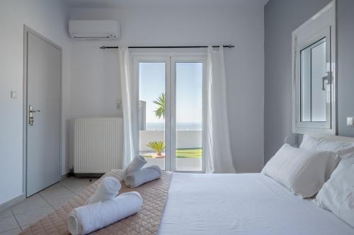a white bedroom with a large white bed and a window at Felix Villa with magic view and heated pool in Ayía Paraskeví