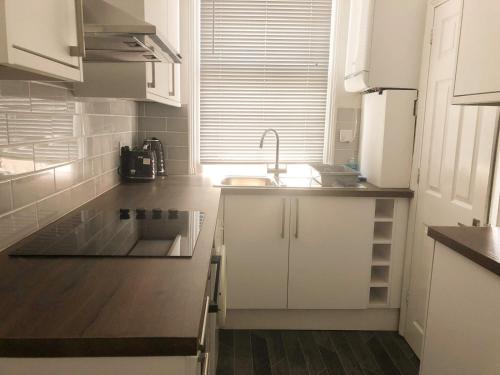 a kitchen with white cabinets and a sink at Spacious 3 bedroom house can sleep 6 in Leeds