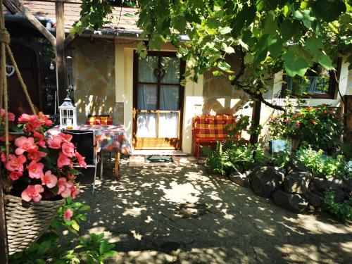 une terrasse couverte d'une maison avec une table et des fleurs dans l'établissement Arlekin Apartman, à Hévíz