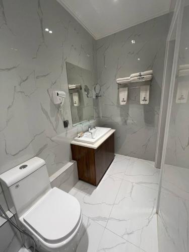 a white bathroom with a toilet and a sink at Termez Palace Hotel & Spa in Termiz