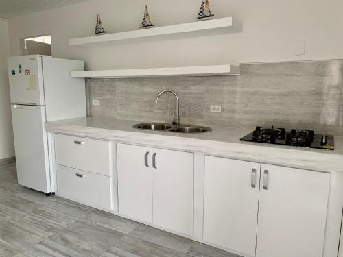 a white kitchen with a sink and a refrigerator at Tu Casita en Aruba in Palm-Eagle Beach