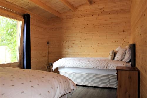 Habitación de madera con 2 camas y ventana en Stunning 5-Bed Cabin in Ashton Under Hill en Evesham
