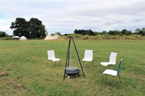 a group of chairs sitting in a field at Stunning 5-Bed Cabin in Ashton Under Hill in Evesham