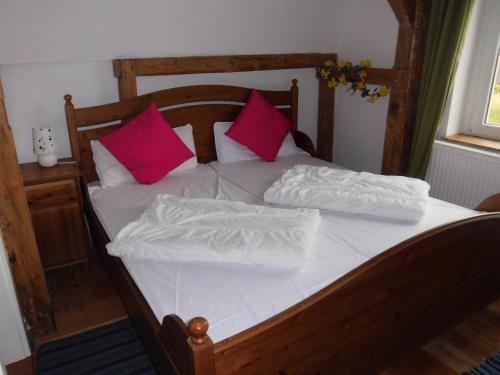 a wooden bed with pink and white pillows on it at Gutshaus Wohlenhagen in Wohlenberg