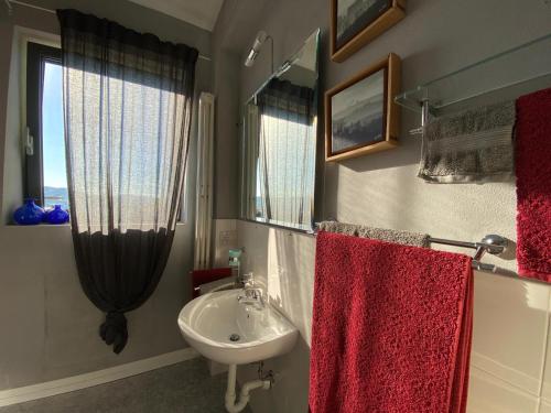 W łazience znajduje się biała umywalka i czerwone ręczniki. w obiekcie Piccolo Nido in Alta Langa /Cosy Studio w mieście Levice
