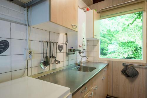 a small kitchen with a sink and a window at Vrijstaande bungalow bij het bos in het Vechtdal in Arriën