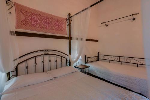a bedroom with two beds with white sheets and a window at Il Monastero in Geremèas