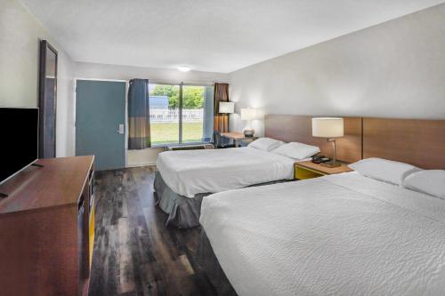 a hotel room with two beds and a desk at Days Inn by Wyndham Owensboro in Owensboro