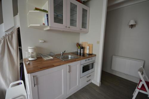 une cuisine avec des armoires blanches et un évier dans l'établissement Charmante maison à 100 m de la plage du Crotoy, au Crotoy