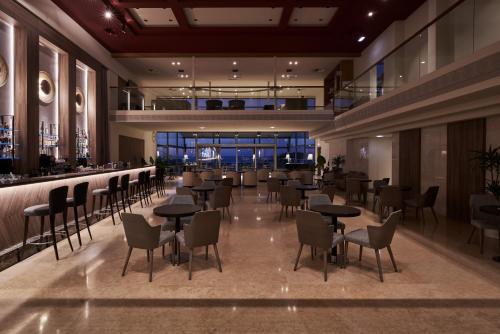 スタロスにあるAtlantica Kalliston Resort - Adults Onlyのテーブルと椅子のあるレストラン、バー