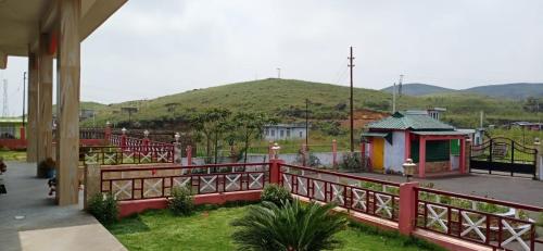 a red fence next to a building with a hill in the background at Sulawado Resort in Cherrapunji