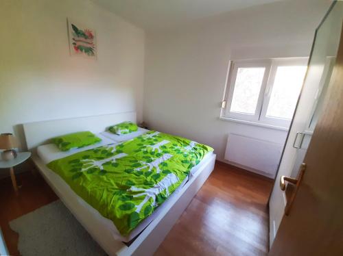 a bedroom with a bed with green sheets and a window at Riverside Vacation House Mrežnica in Donji Zvečaj