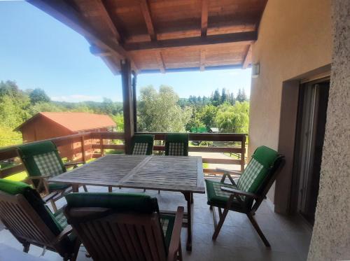a wooden table and chairs on a balcony with a view at Riverside Vacation House Mrežnica in Donji Zvečaj
